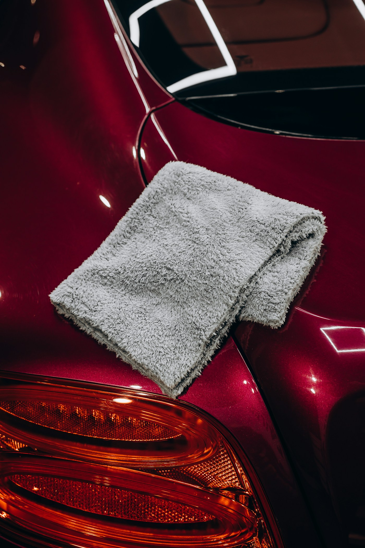 A microfiber detailing cloth on polished red car paint